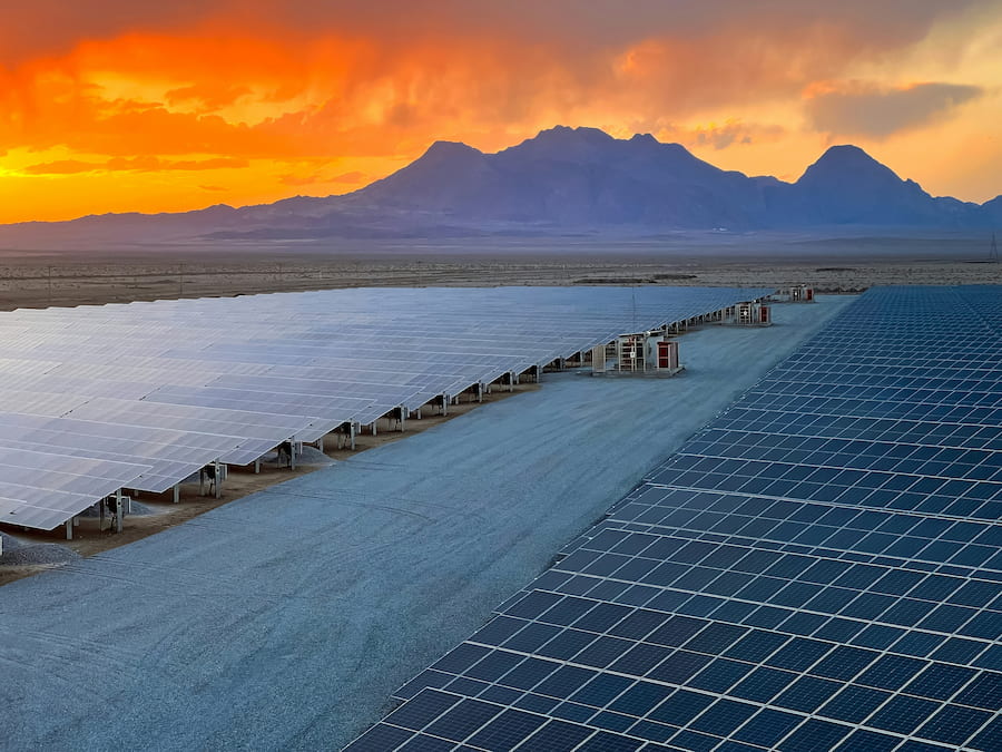 Solar farm at sunset with mountain backdrop